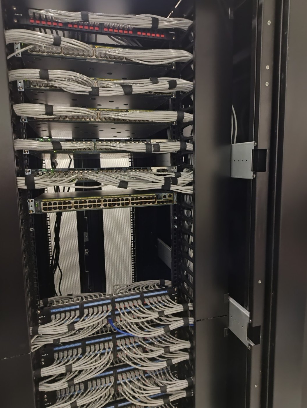Rack padronizado com patch panels, switches e cabos identificados